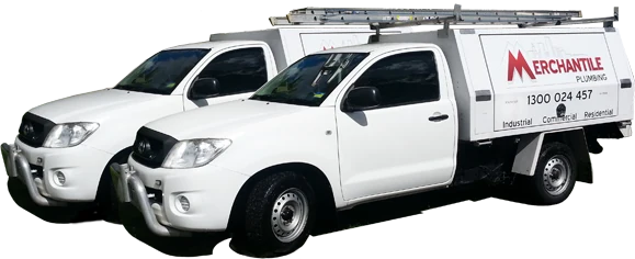 Two white Toyota Hilux service utes with ladder racks and Merchantile Plumbing signwriting on the canopy